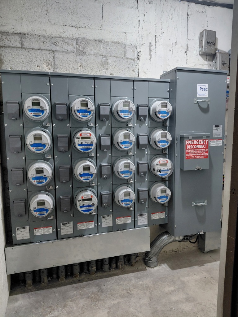 After — New Meter Bank Fully Installed, PSEC Label, Emergency Disconnect, All Units Energized — PSEC Install 2